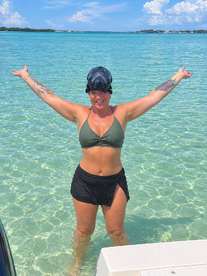 A joyful woman celebrates in the shallow turquoise waters, ready for snorkeling — a perfect moment for adventure and fun in the sun.