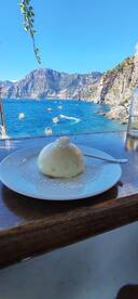 A dessert plate with a scenic view of the coastline and boats in the background, capturing a serene dining experience by the water.