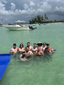 A lively group enjoys a fun day at the sandbar, swimming and sipping drinks in the warm waters — a perfect setting for summer celebrations.