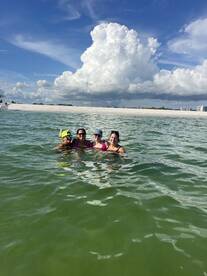 A joyful group of friends enjoys a refreshing swim in clear waters, with a beautiful beach backdrop — perfect for summer adventures and beach outings.