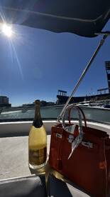 A stylish setup featuring a bottle of champagne and a designer handbag on a boat, perfect for luxurious outings and celebrations on the water.