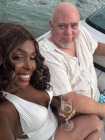 A couple enjoys a moment on a boat, toasting with drinks and capturing a joyful memory on the water — perfect for romantic outings or celebrations.