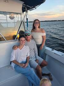 A joyful family poses together on a boat, capturing a memorable moment against a beautiful sunset backdrop — perfect for family outings and celebrations on the water.