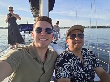 A cheerful group enjoys a sailing trip, capturing memories with a selfie on the deck — perfect for fun outings on the water.