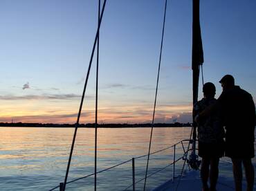 A couple enjoys a romantic moment on a yacht at sunset, creating a picturesque backdrop for unforgettable memories on the water.