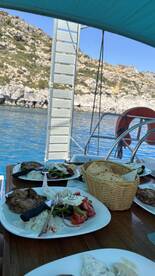 A beautifully arranged meal featuring grilled chicken, fresh salad, and bread, perfect for enjoying onboard while taking in the stunning views of the coastline.