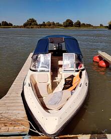 A speedboat docked at a serene waterfront, showcasing its sleek design and inviting seating area — perfect for a day on the water.