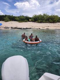 A lively group enjoys a fun day on the water, floating on a mat in a picturesque setting — perfect for beach outings and summer adventures.