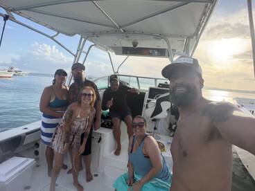 A joyful group poses for a photo on a boat, capturing a memorable moment under the sunset — perfect for celebrating special occasions on the water.