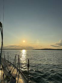 A serene sunset view from the deck of a sailboat, showcasing the tranquil waters and beautiful sky — perfect for peaceful evening cruises.