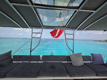 A cozy lounge area on a yacht, featuring comfortable seating and a stunning view of the turquoise waters, perfect for relaxation while cruising.