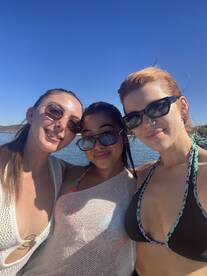 Three friends pose for a cheerful selfie on a sunny day, capturing the joy of their boating adventure together.