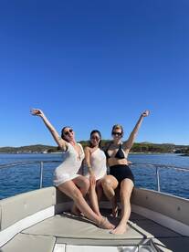 Three friends enjoy a sunny day on a boat, celebrating and having fun together — perfect for memorable outings on the water.