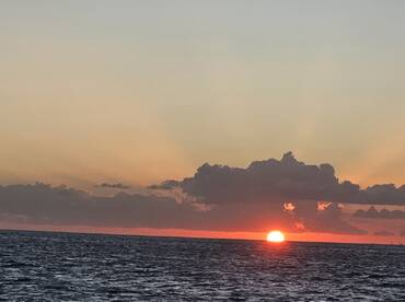 A stunning sunset over the ocean, showcasing vibrant colors as the sun dips below the horizon — a perfect backdrop for evening boat cruises.