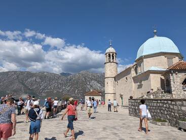 A vibrant scene of tourists exploring a historic site with stunning mountain views in the background, perfect for cultural and sightseeing tours.