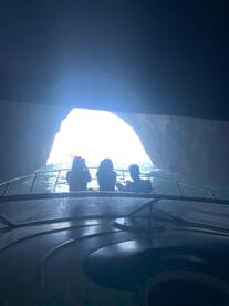 A group of friends enjoys an adventurous boat ride through a cave, capturing the stunning view of light streaming in from the entrance — a perfect moment for exploration and discovery.