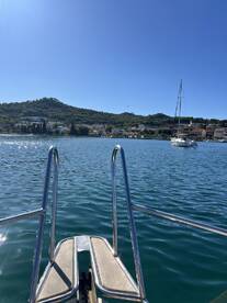 A serene view from the back of a boat, showcasing the calm waters and a distant sailboat, perfect for capturing the essence of a peaceful day on the water.