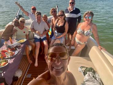 A lively group enjoys a fun day on the water, celebrating with food and drinks aboard a boat — perfect for memorable gatherings and parties.