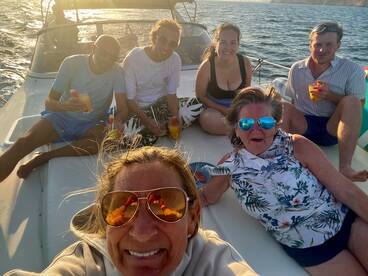 A joyful group enjoys cocktails aboard a boat during a sunset cruise, capturing the essence of fun and relaxation on the water.
