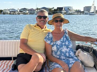 A cheerful couple enjoys a relaxing moment on a boat, surrounded by scenic waterfront views — perfect for a romantic getaway or leisurely day on the water.