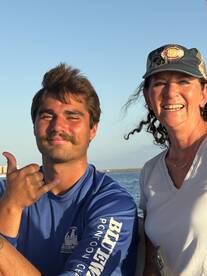 A cheerful duo poses for a photo on a boat, showcasing the joy of a day on the water with friends.