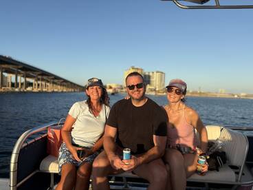 A cheerful group enjoys drinks on a boat, capturing the essence of a fun day on the water with a scenic backdrop of the city skyline.