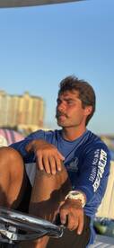 A young man relaxes on the helm of a boat, enjoying the scenic view. Perfect for capturing the essence of a day on the water.