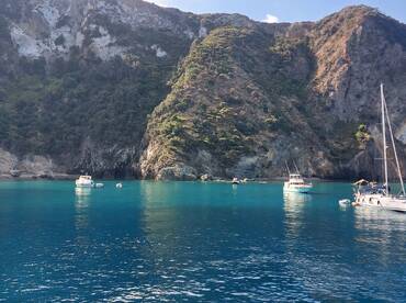 A picturesque view of boats anchored in a serene harbor surrounded by stunning cliffs and crystal-clear waters, perfect for a day of exploration and relaxation.