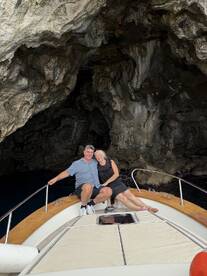 A couple enjoys a romantic moment aboard their boat near a stunning cave, perfect for adventurous outings and memorable experiences on the water.