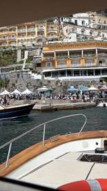 A scenic view from a boat approaching a bustling harbor, showcasing colorful buildings and lively activity along the waterfront — perfect for exploring coastal destinations.