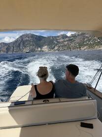 A couple enjoys a scenic boat ride with stunning mountain views in the background, perfect for romantic getaways or leisurely cruises.