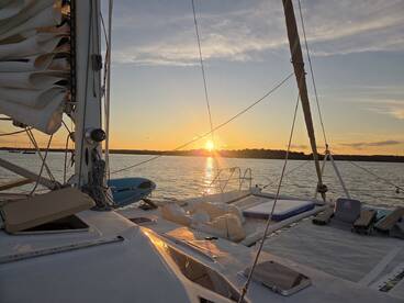 A serene sunset view from the deck of a sailboat, showcasing the tranquil waters and the beauty of nature — perfect for evening cruises.