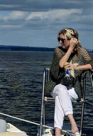 A woman enjoys a refreshing drink while relaxing on the deck of a boat, capturing the essence of leisure and enjoyment on the water.