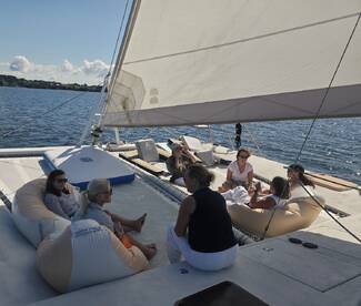 A group of friends relaxes on the deck of a catamaran, enjoying drinks and conversation under the sun — perfect for a day of leisure on the water.