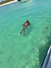A woman enjoys a refreshing swim in the crystal-clear waters, showcasing the perfect beach day experience.