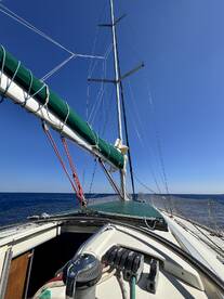 A stunning view of a sailboat's deck and mast against a clear blue sky, showcasing the vessel's structure while underway on open waters.