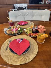 A beautifully arranged dining table on a boat featuring an array of delicious food and cocktails, perfect for a luxurious onboard experience.