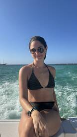 A woman enjoys a sunny day on a boat, smiling against the backdrop of sparkling ocean waters — perfect for a fun day out at sea.
