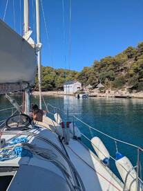 A scenic view from the deck of a sailboat, showcasing a tranquil harbor with a person onboard, perfect for sailing adventures and exploring coastal destinations.