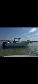 A boat is anchored in shallow waters with people onboard, showcasing a lively day on the water.