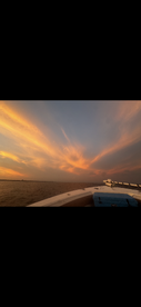 A stunning sunset view from the bow of a boat, showcasing vibrant colors across the sky and calm waters — perfect for evening cruises.