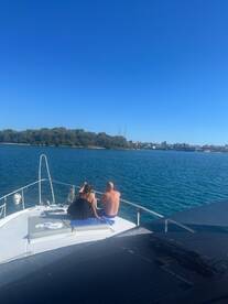 A couple enjoys a serene moment on the deck of a yacht, overlooking beautiful waters and lush greenery — a perfect escape for relaxation and scenic views.
