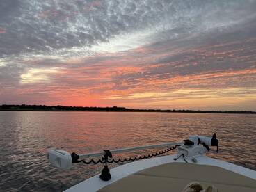 A serene view of a boat at sunset, showcasing the tranquil waters and vibrant sky — perfect for peaceful evening cruises.
