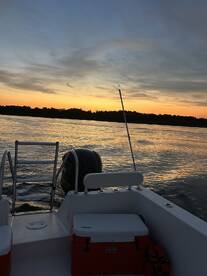 A serene sunset view from the deck of a boat, showcasing the tranquil waters and a beautiful sky — perfect for evening cruises.