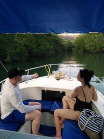 A couple enjoys a serene moment on a boat surrounded by lush mangroves, perfect for a relaxing getaway in nature.