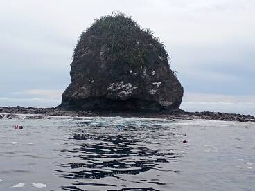 Snorkelers explore the vibrant waters near a striking rock formation, showcasing the beauty of underwater adventures.