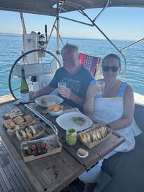 A couple enjoys a delightful meal with drinks aboard a yacht, capturing the essence of a perfect day on the water.