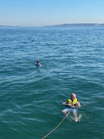 Two individuals enjoy a refreshing swim in clear waters, showcasing the fun and adventure of on-water activities.