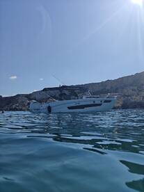 A sleek speedboat anchored in clear waters, surrounded by stunning cliffs — perfect for a day of adventure on the water.