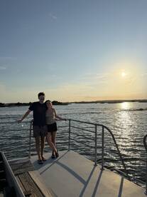 A couple enjoys a romantic moment on the deck of a boat during sunset, capturing the essence of a perfect evening on the water.
